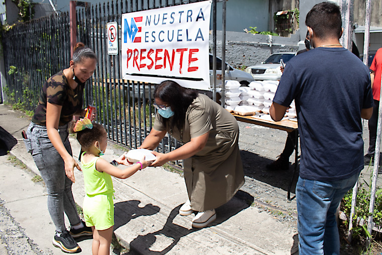 Ana Yris Guzmán le entrega almuerzo a niña en Nuestra Escuela. (Foto/Suministrada)